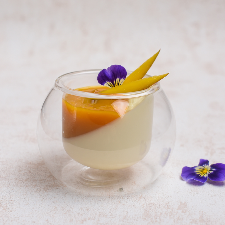 Pannacotta in a glass made sideways with mango coulis